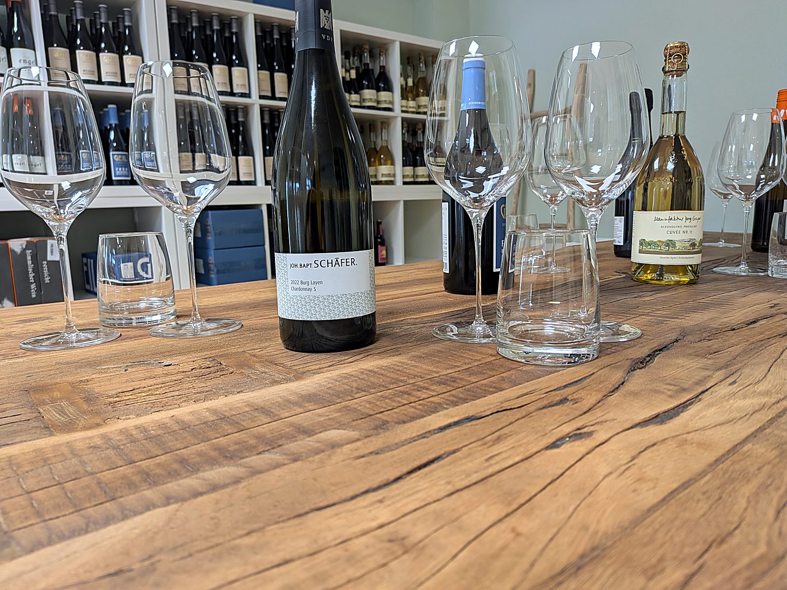 Großer Holztisch mit Gläsern und geöffneten Flaschen
